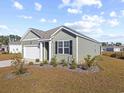 View of a green-sided house with a white garage door and neatly landscaped yard at 1143 Sennema Circle, Myrtle Beach, SC 29588