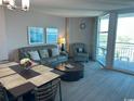 Living room with a couch, armchair, dining table, and large window with a view at 2301 S Ocean Blvd. # 1002, North Myrtle Beach, SC 29582
