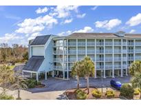 Exterior view of a three-story building with parking and palm trees at 14290 Ocean Hwy. # 406, Pawleys Island, SC 29585