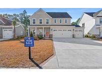 Two-story house with beige siding, three-car garage, and a landscaped lawn at 2321 Vera Way, Longs, SC 29568