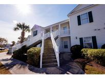 Two-story building with white siding, green shutters, and a stairway leading to the second floor at 4935 Crab Pond Ct. # 202, Myrtle Beach, SC 29579