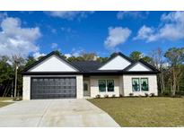 New construction home with white and black exterior, two-car garage, and nicely landscaped lawn at 205 Brush Ct., Little River, SC 29566