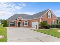 Brick home with a two-car garage and landscaped yard at 305 Lyndhurst Ct., Myrtle Beach, SC 29579