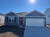 Gray house with red door, white garage door, and landscaping at 330 Cheerful Way, Little River, SC 29566