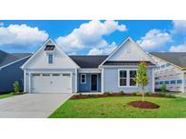 Two-story light blue house with white accents, two-car garage, and landscaped lawn at 1958 Woodrush Loop, Little River, SC 29566