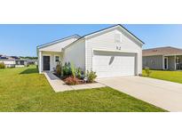 House exterior showcasing a white vinyl sided home with a two-car garage and well-manicured lawn at 530 Carrick Loop, Longs, SC 29568