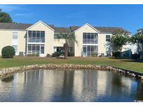 Exterior of a yellow two-story building with pond and landscaping at 8925 Duckview Dr. # H, Surfside Beach, SC 29575