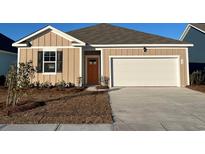 Beige house with orange door, two-car garage, and landscaped yard at 580 Duvall St., Longs, SC 29568