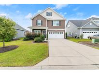 Two-story home with brown siding, white garage door, and landscaped lawn at 6215 Chadderton Circle, Myrtle Beach, SC 29579