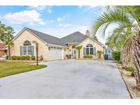 Quaint yellow house with a two car garage and landscaped yard at 255 Pilot House Dr., Myrtle Beach, SC 29577