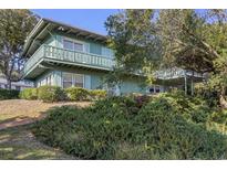 Two-story house with a balcony, surrounded by lush greenery at 1000 Strand Ave., North Myrtle Beach, SC 29582