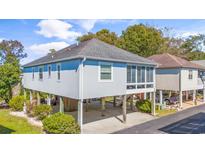 Elevated beach home with gray siding, sunroom, and ample parking at 820 9Th Ave. S, North Myrtle Beach, SC 29582