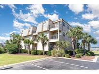 Two-story building with light-colored exterior and palm trees at 1582 S Waccamaw Dr. # 60, Garden City Beach, SC 29576
