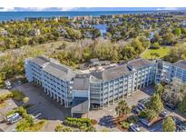 Aerial view of a coastal community with a large building and ocean in the distance at 14290 Ocean Hwy. # 202, Pawleys Island, SC 29585