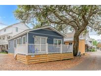 Charming blue cottage with a deck and white railing under a large tree at 6001-1157 S Kings Hwy., Myrtle Beach, SC 29575