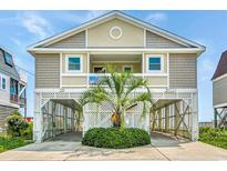 Two-story home with elevated parking and a palm tree at 551 S Waccamaw Dr., Garden City Beach, SC 29576