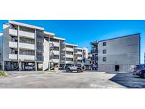 Exterior view of a beach condo building with parking and cars at 814 N Waccamaw Dr. # 311, Garden City Beach, SC 29576
