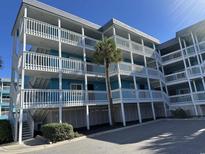 Three-story building with light blue exterior, balconies, and a palm tree in front at 700 N Waccamaw Dr. # 319, Garden City Beach, SC 29576