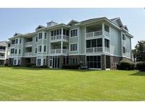 Three-story building with light green siding, balconies, and lawn at 4893 Magnolia Pointe Ln. # 103, Myrtle Beach, SC 29577
