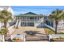 Two-story home with a green roof, white fence, and a driveway at 310 34Th Ave. N, North Myrtle Beach, SC 29582