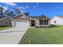 New construction home with a tan exterior, white garage door, and landscaped lawn at 647 Woodside Dr., Conway, SC 29526