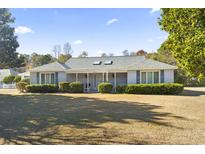 Charming single-story home with a covered front porch, lush landscaping, and a large front yard at 601 Saint Johns Circle, Longs, SC 29568