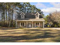 Two-story house with gray siding, porch, and landscaping at 3940 Loblolly Ave., Little River, SC 29566