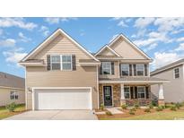 Two-story home with tan siding, white garage door, and stone accents at 561 Slaty Dr., Myrtle Beach, SC 29588