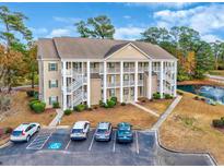 Exterior view of a 3 story building with parking and a pond at 5804 Longwood Dr. # 301, Murrells Inlet, SC 29576