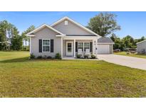 One-story home with gray siding, a covered porch, and a two-car garage at 612 Pine Oaks Farm Rd., Aynor, SC 29511