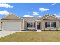Newly constructed home with a beige exterior, attached garage, and landscaped lawn at 637 Woodside Dr., Conway, SC 29526