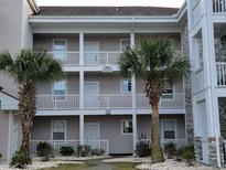 Two-story condo building with light gray siding, white trim, and palm trees at 4717 Wild Iris Dr. # 29-303, Myrtle Beach, SC 29577