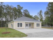 Newly constructed home with gray roof and light beige siding, spacious driveway and green lawn at 5595 Dinkler Ave., Loris, SC 29569