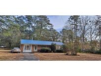 Brick house with blue metal roof, a car parked in the driveway, and mature trees at 560 Indian Hut Rd., Georgetown, SC 29440