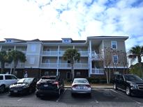 Two-story condo building with light beige siding, balconies, and ample parking at 374 Wild Wing Blvd. # J, Conway, SC 29526