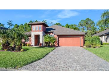Beautiful two-story house with a reddish exterior, paver driveway and landscaping at 660 Aldenham Ln, Ormond Beach, FL 32174