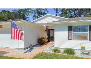 White house exterior with walkway, landscaping, and American flag at 32676 Oak Park Dr, Leesburg, FL 34748