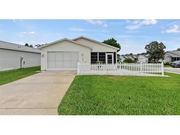 One-story home with attached garage and white picket fence, nicely landscaped lawn at 2590 Acosta Ct, The Villages, FL 32162