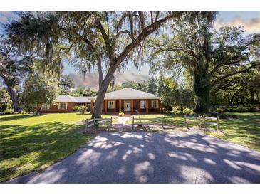 Brick home nestled on a spacious lot with mature trees and a long driveway at 3554 County Road 216, Oxford, FL 34484