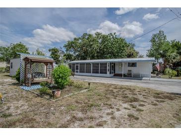 Mobile home exterior with covered porch, shed, and landscaped yard at 1306 Westland Dr, Tavares, FL 32778