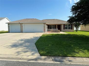 Single-story home with three-car garage and well-maintained lawn at 12046 Ne 51St Cir, Oxford, FL 34484