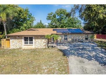 Single-story home with stone exterior, solar panels, and a long driveway at 3460 Laurel Dr, Mount Dora, FL 32757