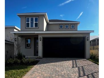 Two-story house with gray siding, black garage door, and paved driveway at 2003 Sunshine Peak Dr, Minneola, FL 34715