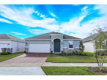 Newly constructed home with gray exterior, brick driveway and landscaping at 5814 Wallis Ln, Saint Cloud, FL 34771