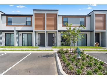 Modern townhome exterior with gray and brown accents, landscaping, and parking at 8763 Zen Dr, Kissimmee, FL 34747