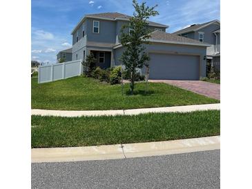 Two-story house with gray exterior, two-car garage, and landscaped front yard at 6904 Church Lake St, Groveland, FL 34736