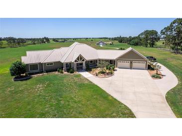 Aerial view of a luxurious ranch-style home with a large yard and detached garage at 2499 Nw 102Nd Blvd, Wildwood, FL 34785