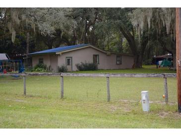 Ranch home with a large backyard and wooden fence at 16640 Ne 148Th Terrace Rd, Fort Mc Coy, FL 32134