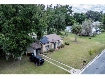 Aerial view of a charming house with a spacious yard and solar panels at 750 N Kentucky Ave, Umatilla, FL 32784