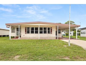 Front view of a single-story manufactured home with a covered carport and well-maintained lawn at 1209 Apache Cir, Tavares, FL 32778